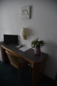 un escritorio con ordenador y un jarrón de flores. en Pension Brenz, en Sontheim an der Brenz
