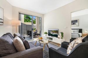 a living room with a couch and a tv at CENTRAL NO 5 LUXURY APARTMENT in Kiama