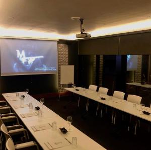 uma sala de conferências com mesas e cadeiras brancas e um ecrã em Emens hotel em Esmirna