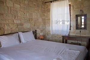 1 dormitorio con cama y pared de piedra en Esperides Stone Houses, en Palaikastro