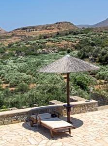 a patio with a table and an umbrella and benches at Esperides Stone Houses in Palekastron