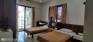 a woman standing in a hotel room with two beds at Aashiyana Inn in Nashik