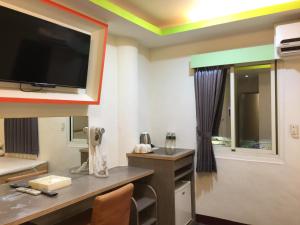 斗六的住宿－微旅時尚旅店，一间墙上配有电视和书桌的房间