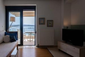 a living room with a couch and a television and a balcony at Sea & Town Getaway in Chania