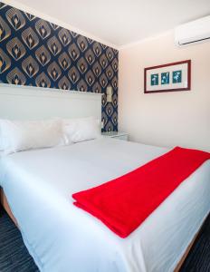 a bedroom with a white bed with a red blanket on it at Florida Park Hotel, Florida Road in Durban +93 photos