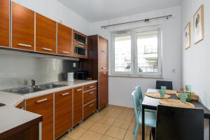 una cocina con armarios de madera y una mesa con sillas. en Sleepway Apartments - Garbary 95-112a, en Poznan