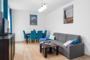 sala de estar con sofá y mesa con sillas azules en Sleepway Apartments - Garbary 95-112a, en Poznan