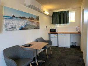 a room with a table and chairs and a kitchen at Mariner Motel in Laurieton