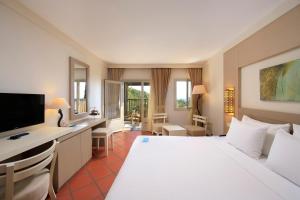 um quarto de hotel com uma cama branca e uma secretária em Hapimag Sea Garden Resort em Yaliciftlik