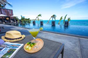 a drink on a table next to a swimming pool at Pavilion Pool Residence Samui - SHA Extra Plus in Lamai
