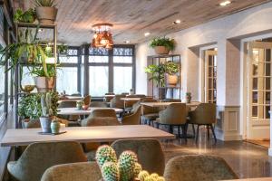 ein Restaurant mit Tischen, Stühlen und Topfpflanzen in der Unterkunft Hotel Restaurant De Wolfsberg in Groesbeek