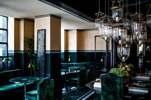 a restaurant with green chairs and tables and chandeliers at Monsieur George Hotel & Spa - Champs-Elysées in Paris