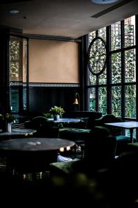 a room with tables and chairs and windows at Monsieur George Hotel & Spa - Champs-Elysées in Paris