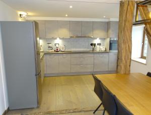 eine Küche mit einem Holztisch und einem Kühlschrank in der Unterkunft Au Frêne Centenaire in Bras