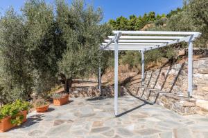 a white pergola in a garden with trees at Kalithea Studios in Stafylos