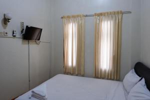 a small bedroom with a bed and a television at Khresna Guest House Malioboro Mitra RedDoorz in Yogyakarta