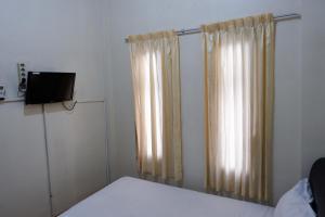1 dormitorio con cama y cortina en Khresna Guest House Malioboro Mitra RedDoorz en Yogyakarta