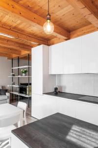 Il comprend une cuisine avec des placards blancs et un plafond en bois. dans l'établissement Casa Langhe, à Roddi