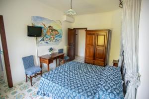 een slaapkamer met een bed, een bureau en een televisie bij Nido Degli Dei in Agerola