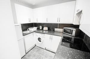 a kitchen with a washing machine and a microwave at Argyll Apartments in Glasgow