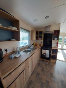 een keuken met houten kasten, een wastafel en een fornuis bij Rustling Pines at Knaresborough Lido in Harrogate