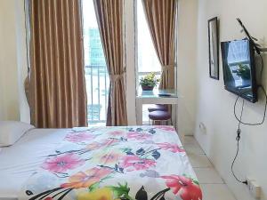 - une chambre avec un lit doté d'une couverture fleurie et d'une télévision dans l'établissement Apartemen Sentra Timur Residence - Cheap Inn Tower Orange, à Jakarta
