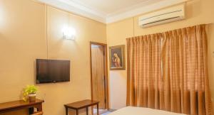 a hotel room with a television and a bed at Hanu Reddy Residences Wallace Garden in Chennai