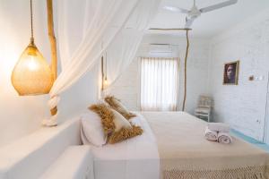 a white bedroom with a bed and a window at Guru Canggu in Canggu