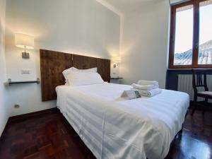 Cette chambre comprend un grand lit blanc et une fenêtre. dans l'établissement Hotel La Fortezza, à Assise