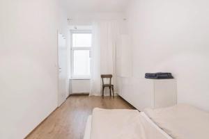 a white room with a bed and a chair at DESIGN APARTMENT PASETTI in Vienna