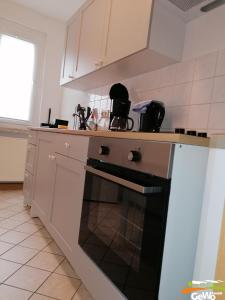 a kitchen with white cabinets and a black oven at Ferienwohnung Karl 54 in Gelenau
