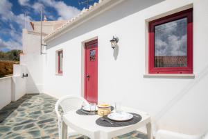 une maison blanche avec une table blanche et une porte rouge dans l'établissement C14 - Casa da Luz, à Luz