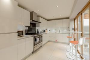 una cocina blanca con electrodomésticos blancos y sillas naranjas en Destiny Scotland - Q-Residence, en Edimburgo