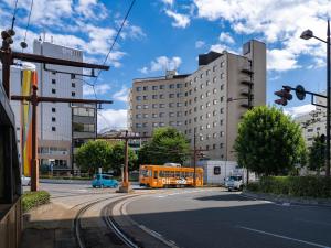 einen orangenen Bus, der in einer Stadt eine Straße entlangfährt in der Unterkunft The OneFive Okayama in Okayama