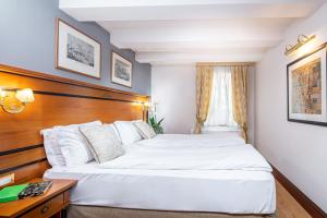 um quarto de hotel com duas camas e uma secretária em All’Angelo Art Hotel em Veneza