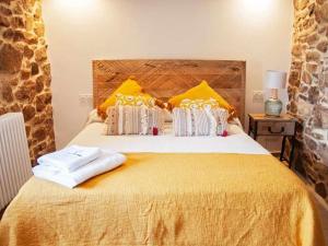 - une chambre dotée d'un grand lit avec des oreillers jaunes et blancs dans l'établissement O Forno Casa Ferrador Ribeira Sacra, à Sober