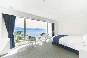 a bedroom with a bed and a view of the ocean at Hotel The Scene in Setouchi