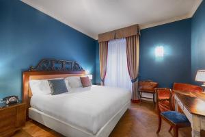 a bedroom with a bed, chair, desk and a lamp at Albergo Posta Marcucci in Bagno Vignoni