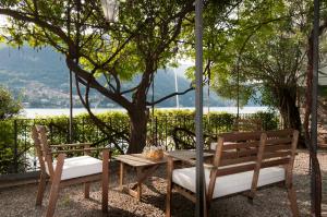 un tavolo e due sedie seduti accanto a un albero di Villa Nina Relais Boutique B&B a Carate Urio
