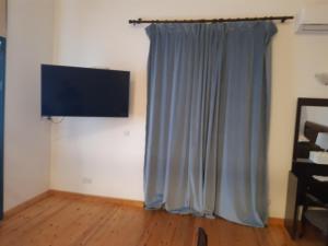 a room with a blue curtain and a flat screen tv at Theoxenia in Kalopanayiotis