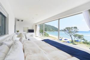 a white bedroom with a large bed and a large window at Hotel The Scene in Setouchi