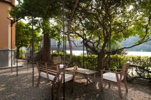 Villa Nina Relais Boutique B&B في Carate Urio: طاولة و كرسيين جالسين تحت شجرة