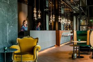 un bar avec une chaise jaune et une femme dans un miroir dans l'établissement Motel One Salzburg-Mirabell, à Salzbourg