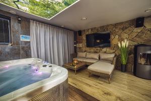 a room with a tub and a couch and a tv at Apartmány Lacov Dom in Klčov