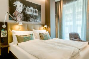 Un dormitorio con una gran cama blanca y una ventana en Motel One Salzburg-Mirabell, en Salzburgo