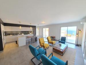 a living room with blue chairs and a kitchen at St-Florent Appartement neuf vue mer panoramique piscine 4 chambres - MOR401 in Saint-Florent