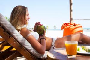 a woman sitting in a chair with a fruit and a drink at Windtown Beach Hotel in Cumbuco