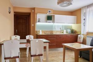 een keuken met een tafel en stoelen en een keuken met witte kasten bij Apartamenty Smrek Poronin in Poronin