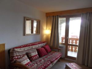 een woonkamer met een bank en een raam bij travelski home classic - Résidence Themis in La Plagne