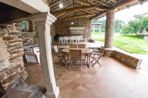 a patio with a table and chairs in a stone building at Hotel O Pozo in O Pino 